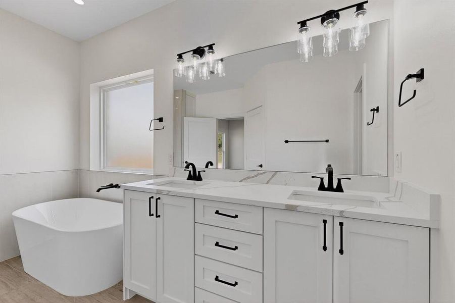 Full bath with a freestanding bath, double vanity, and light wood finished floors