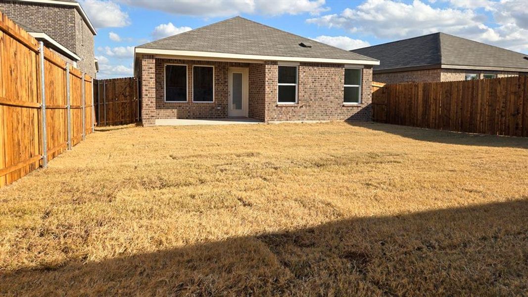 Rear view of property featuring brick siding, a patio area, a fenced backyard, and a shingled roof