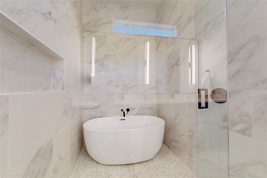 Bathroom featuring tile walls and a tub to relax in