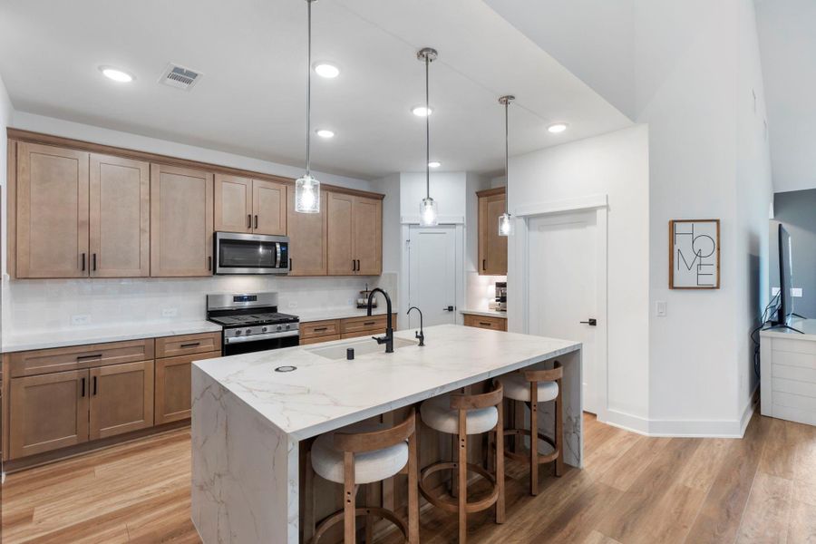 This modern kitchen features sleek wooden cabinetry, stainless steel appliances, and a central island with a marble countertop and seating. Pendant lighting adds elegance, while the open layout offers ample space for cooking and entertaining. This modern kitchen features sleek wooden cabinetry, stainless steel appliances, and a central island with a marble countertop and seating. Pendant lighting adds elegance, while the open layout offers ample space for cooking and entertaining.