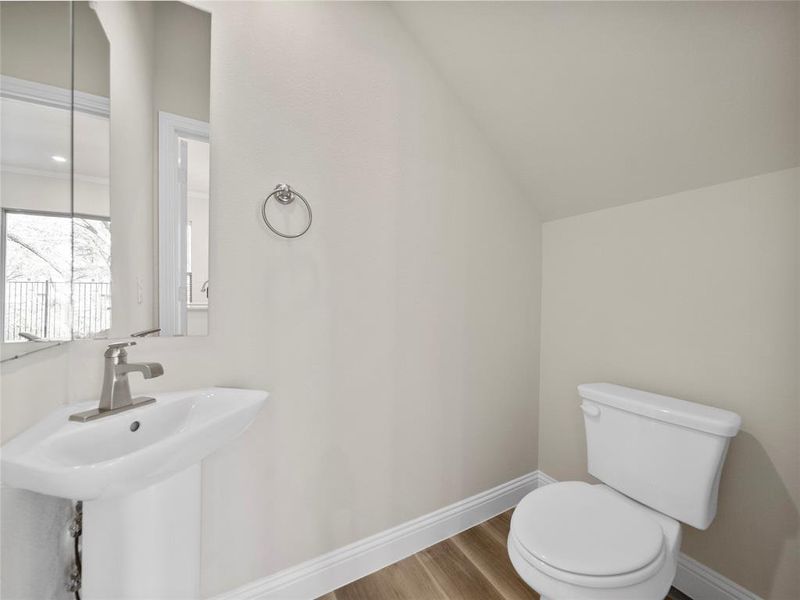Half bath featuring a sink, wood finished floors, toilet, and baseboards
