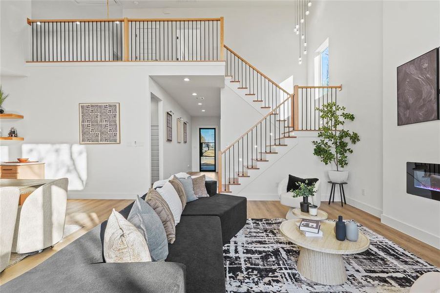 Living room with light wood finished floors, a high ceiling, and a glass covered fireplace