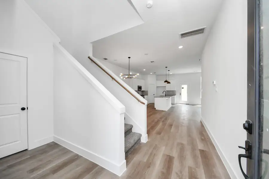 Entry & Living Area – Welcoming entry opens to a spacious open-concept living area with modern lighting, durable wood-look flooring, and a bright, airy feel.