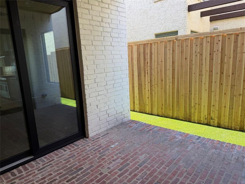 Covered brick patio with turfed & gated yard