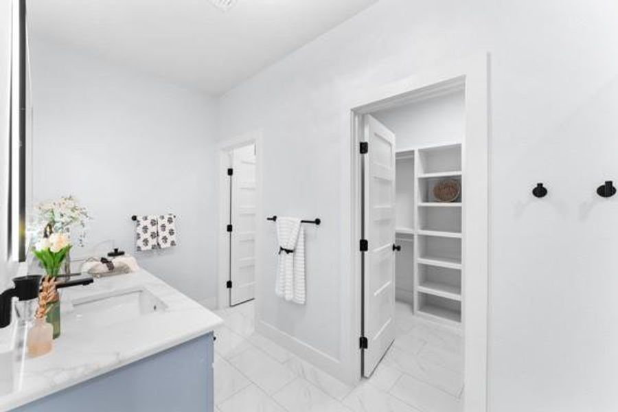Full bathroom with a spacious closet, double vanity, and light marble finish floors Full bathroom with a spacious closet, double vanity, and light marble finish floors