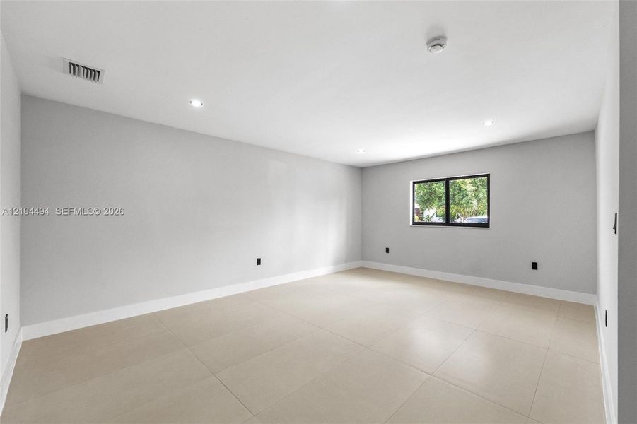 Interior space featuring neutral wall tones, large-format tile flooring, recessed ceiling lighting, and a single window with a black frame