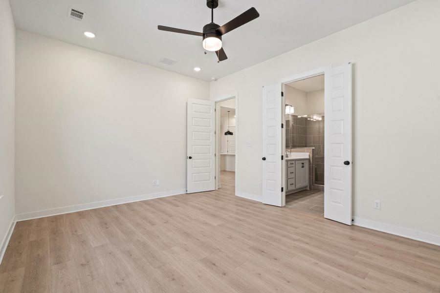 Unfurnished bedroom featuring ceiling fan, ensuite bathroom, light wood finished floors, and recessed lighting