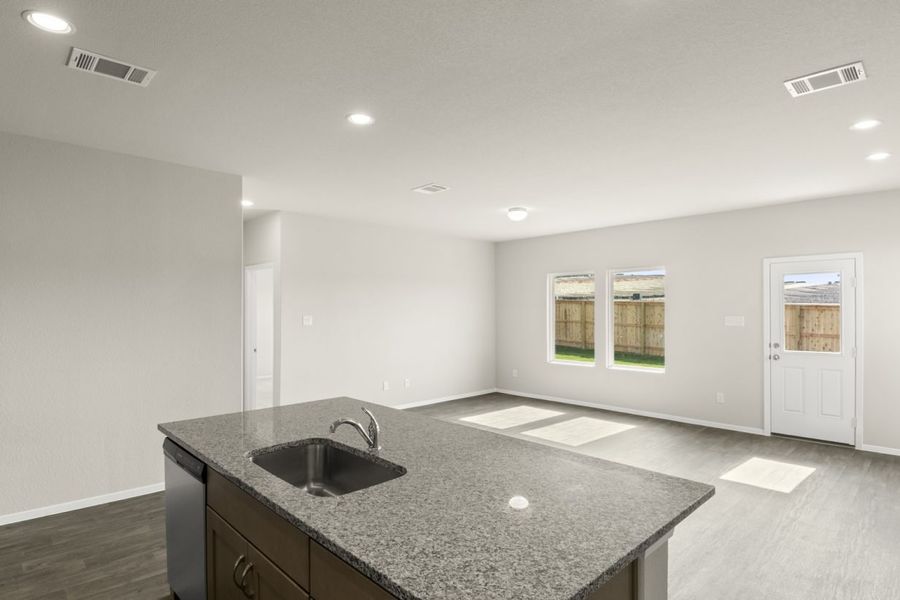 Image of a kitchen overview with a granite center island and cream walls with windows