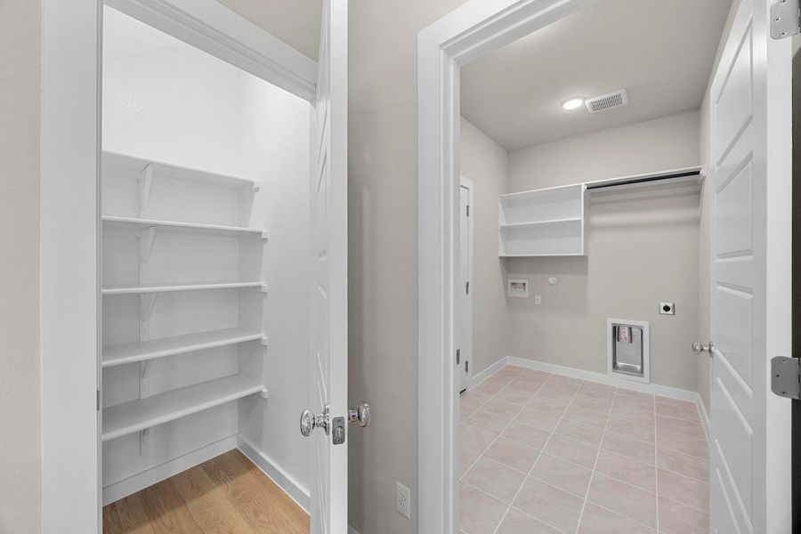 Functional laundry room offers built-in shelving, hanging space, and tiled floors for easy maintenance. Functional laundry room offers built-in shelving, hanging space, and tiled floors for easy maintenance.