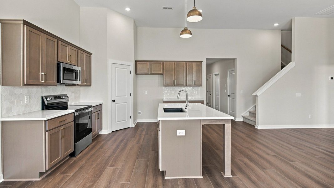 Kitchen Layout with ceramic tile backsplash, quartz countertops, and kitchen island