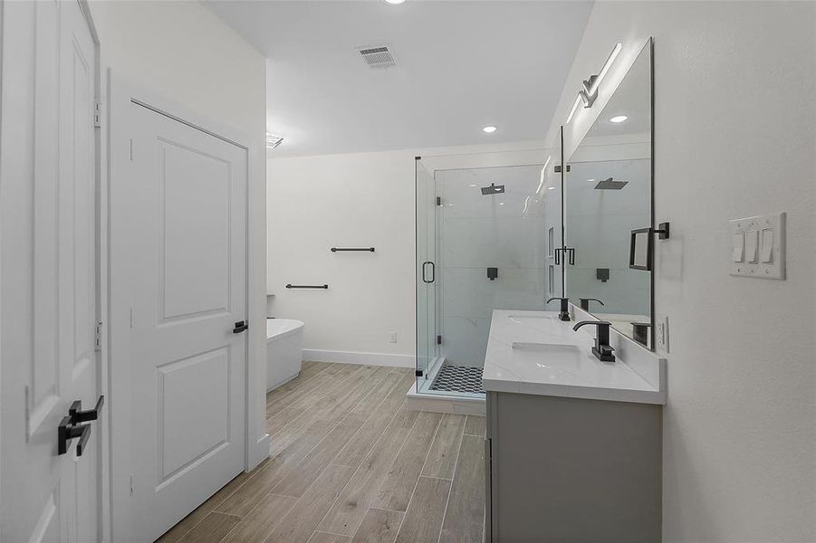 Featuring a spa-like atmosphere, the bathroom boasts a soaking tub, a spacious walk-in shower, and dual vanities accented with sleek countertops and designer fixtures.