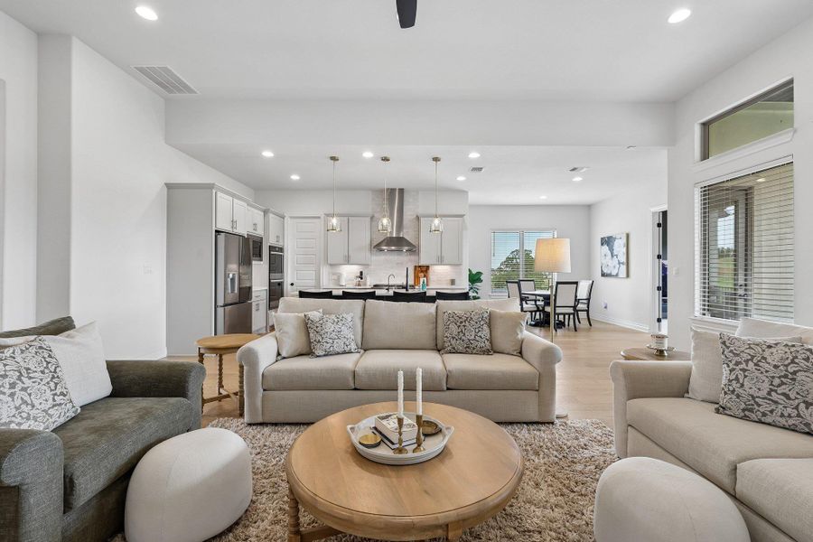 Open-concept living area featuring light wood-finish flooring, recessed lighting, and a contemporary ceiling fan