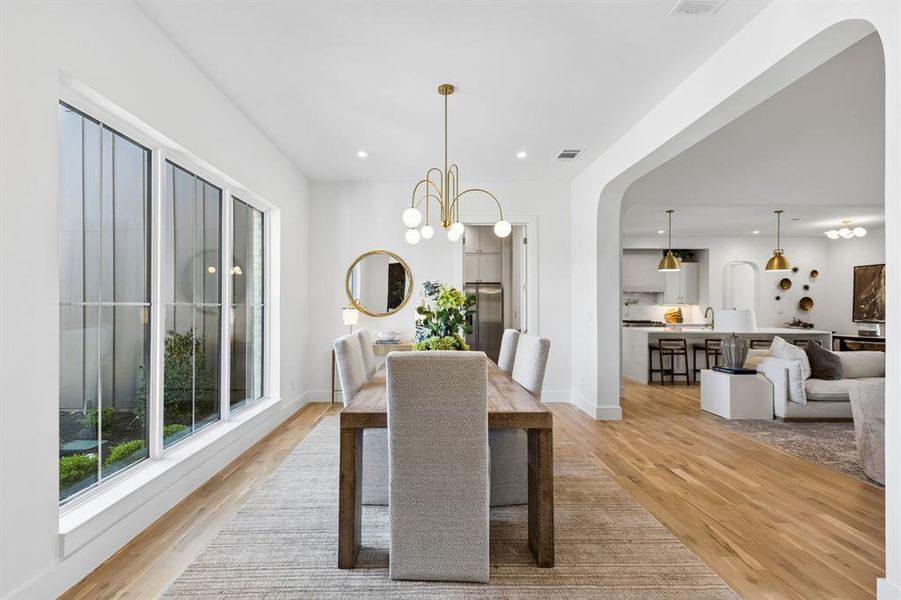 Dining space featuring suspended lighting, arched walkways, and light wood finished floors