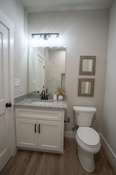 Bathroom featuring wood finished floors, vanity, toilet, and baseboards