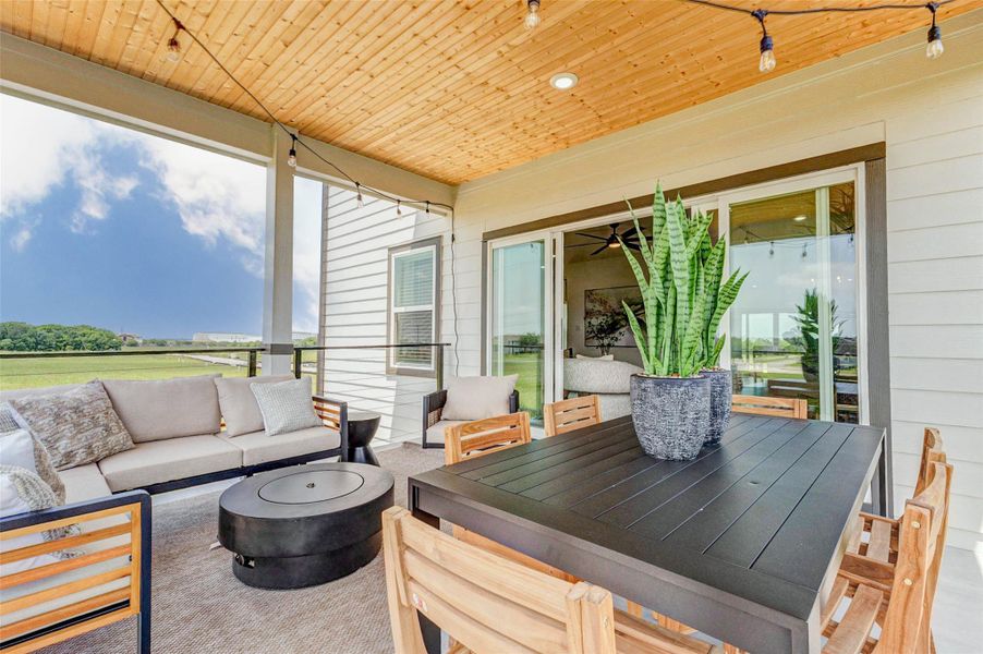 This outdoor living area offers a perfect balance of dining and relaxation, with a spacious table for meals and a cozy lounge setup for conversation. The sliding glass doors connect the patio to the interior, enhancing flow and convenience. Thoughtful details like string lights and natural textures elevate the overall experience. The picture shown is from the model home with the same floor plan, Rev floor plan.
