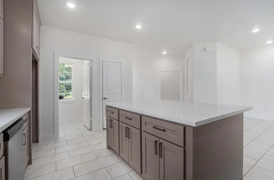 This modern kitchen features a large marble-topped island with ample cabinetry, sleek tile flooring, and plenty of natural light from a nearby window. This modern kitchen features a large marble-topped island with ample cabinetry, sleek tile flooring, and plenty of natural light from a nearby window.