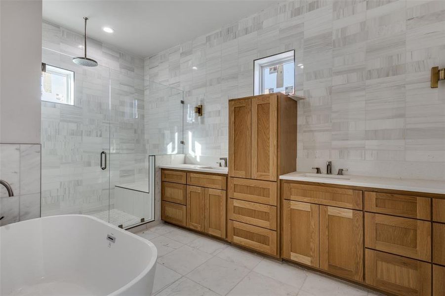 Bathroom with vanity, walk in shower, soaking tub and tile walls.  This Home is under construction and is not subject property for sale but representative of finish out in #110.