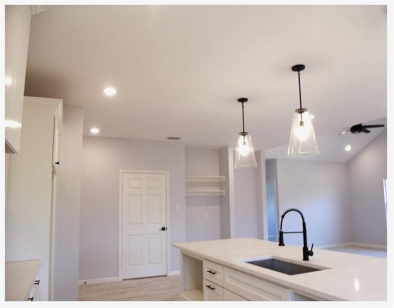 Kitchen with sink, white cabinetry, light hardwood / wood-style flooring, and pendant lighting