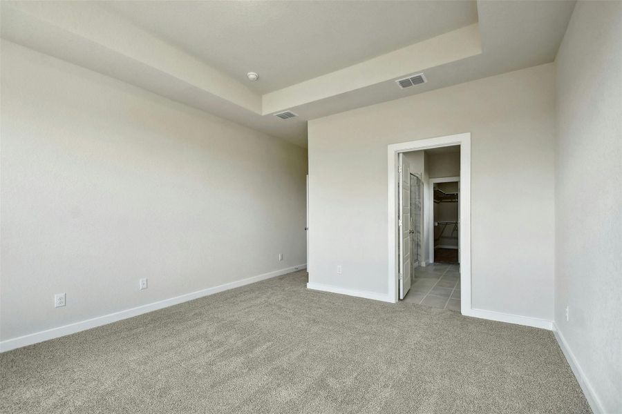 Empty room featuring light colored carpet and a tray ceiling