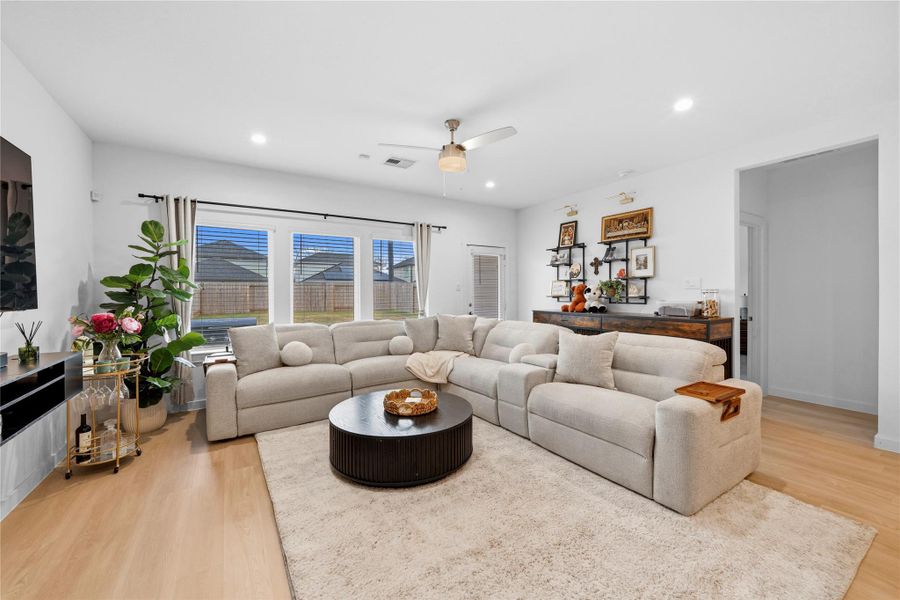 Bathed in natural light, the living room features expansive windows and seamless access to the backyard, all grounded by elegant, light-toned wood-look flooring for a bright, contemporary ambiance. Bathed in natural light, the living room features expansive windows and seamless access to the backyard, all grounded by elegant, light-toned wood-look flooring for a bright, contemporary ambiance.