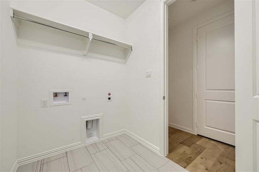 Washroom with hookup for a washing machine, light hardwood / wood-style flooring, electric dryer hookup, and hookup for a gas dryer