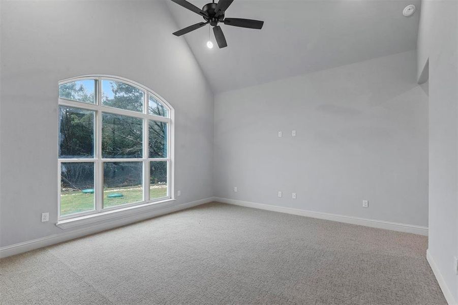 Carpeted spare room with high vaulted ceiling and ceiling fan