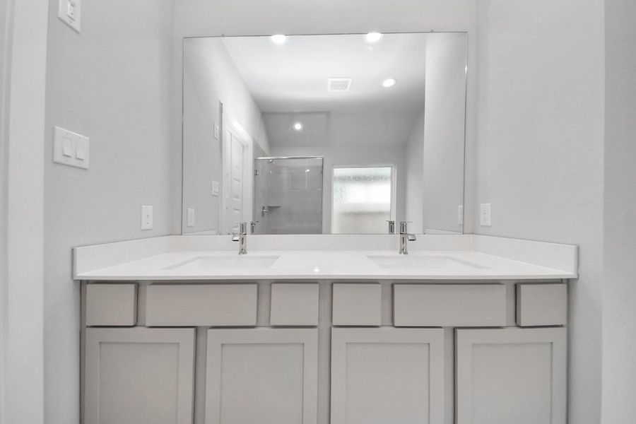 Elevate your daily routine at the elegant vanity, now equipped with double sinks, light countertops, modern hardware, and beautiful recessed lights.
