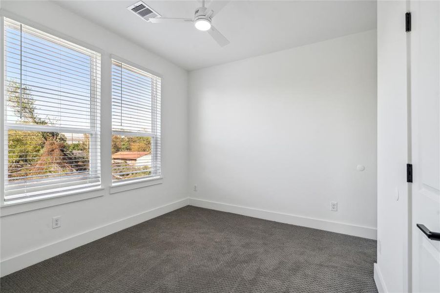 Secondary bedroom with large windows allowing for plenty of natural light, complemented by a ceiling fan for added comfort and a neutral color palette for easy customization.