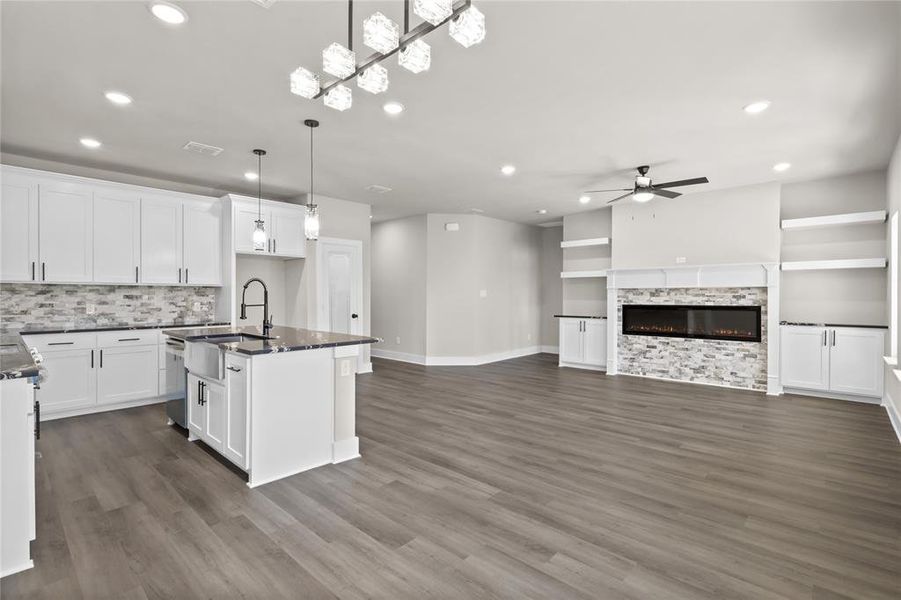 Kitchen with sink, a kitchen island with sink, hanging light fixtures, and white cabinets