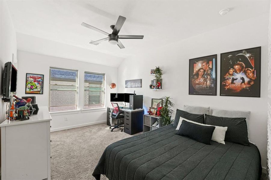 Bedroom featuring light colored carpet, a ceiling fan, an office area, and lofted ceiling