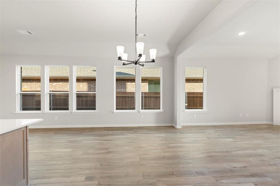 Unfurnished dining area with a chandelier and light wood-style flooring Unfurnished dining area with a chandelier and light wood-style flooring