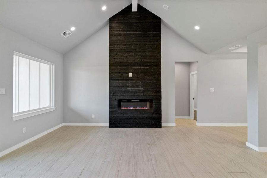 Unfurnished living room with a fireplace, light wood-type flooring, high vaulted ceiling, and beamed ceiling