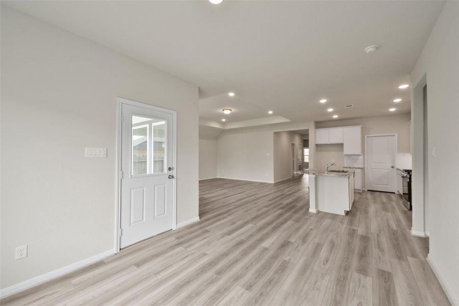 Sun-drenched living area featuring recessed lighting, light wood floors, and direct access to a fenced backyard.