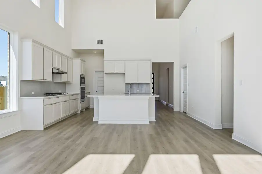 Kitchen with white cabinets, tasteful backsplash, healthy amount of natural light, and light wood finished floors