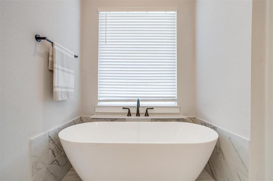 Bathroom with a healthy amount of sunlight, tile walls, and a soaking tub to relax in