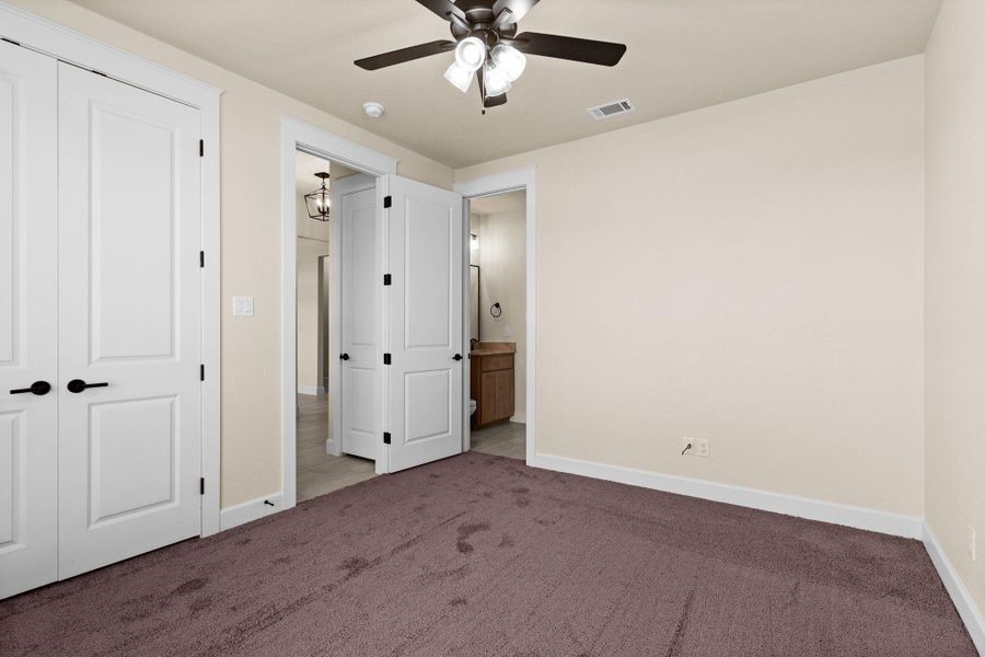 Unfurnished bedroom with carpet flooring, a closet, ceiling fan, and ensuite bath Unfurnished bedroom with carpet flooring, a closet, ceiling fan, and ensuite bath