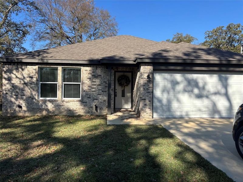 View of front of property featuring roof with shingles, brick siding, an attached garage, and a front yard View of front of property featuring roof with shingles, brick siding, an attached garage, and a front yard