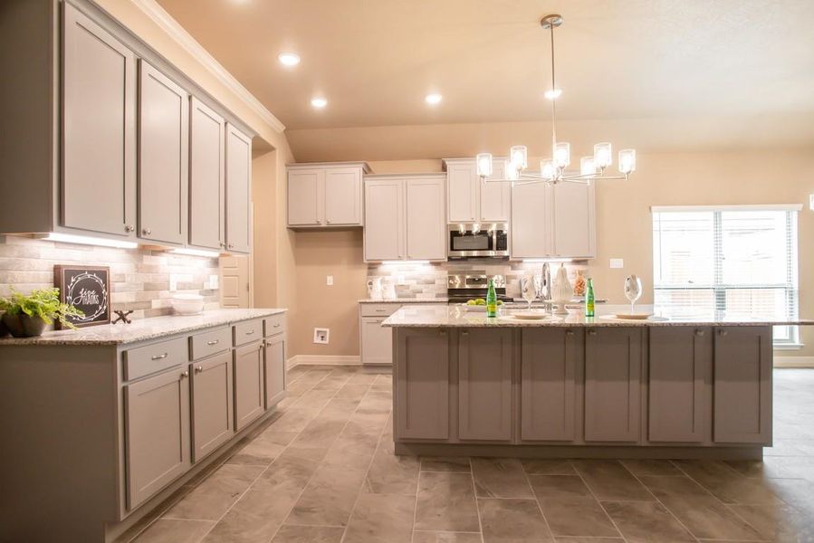 Kitchen featuring backsplash, decorative light fixtures, a center island with sink, stainless steel appliances, and recessed lighting