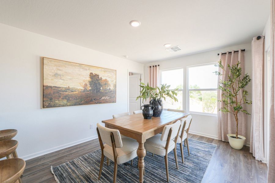 A dining room table with chairs and a painting on the wall.