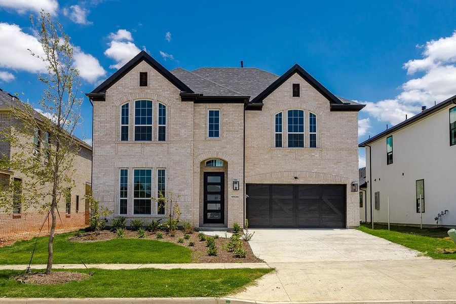 View of front of property featuring a garage and a front lawn