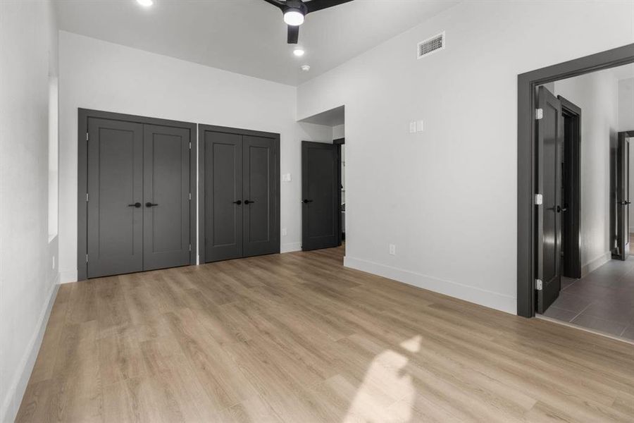 Unfurnished bedroom with two closets, light wood-style flooring, and ceiling fan
