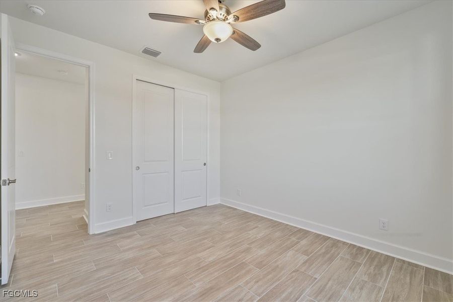 Unfurnished bedroom with wood finish floors, ceiling fan, and a closet