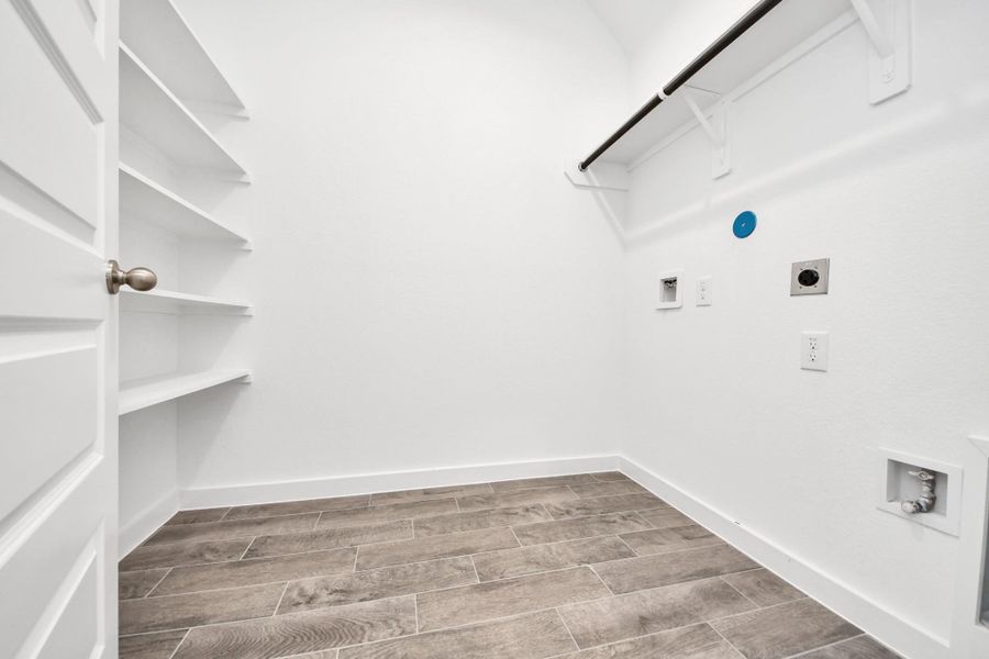 A perfect blend of functionality and comfort. Capture the essence of easy living with a first-floor laundry room, thoughtfully equipped with shelving for effortless organization. Both electric and gas connections available. Sample photo of completed home with similar floor plan. Actual colors and selections may vary.