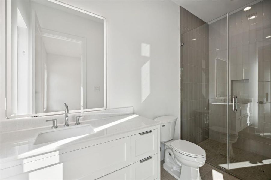 This secondary bathroom features a white vanity with sleek lines, a rectangular undermount sink, and marble countertop creates a clean and airy atmosphere.