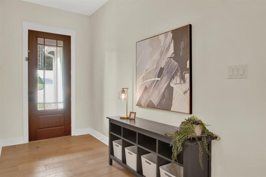 This is a well-lit entry space featuring natural hardwood floors.