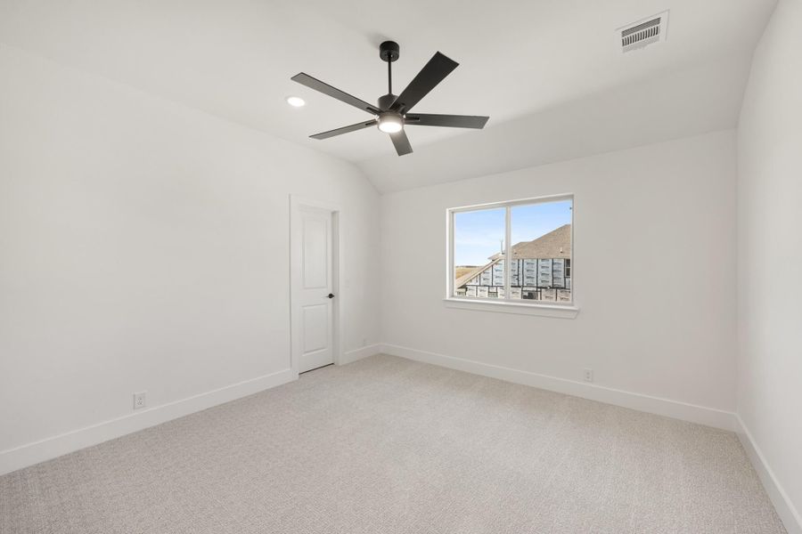 Empty bedroom with vaulted ceiling, black ceiling fan, carpet flooring, and single window