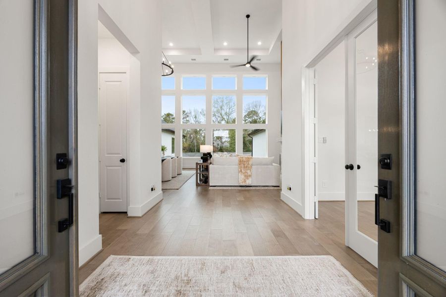 A bright, spacious entryway leading to the living area with high ceilings and large windows, offering plenty of natural light and a modern, open feel.