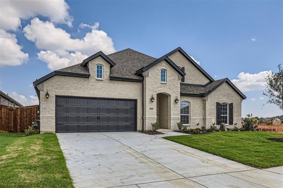 French country inspired facade with a garage and a front lawn