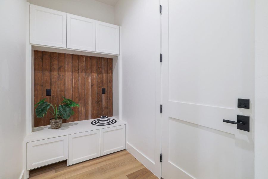 Built-in mudroom bench with three storage cabinets and a wood-finish accent wall