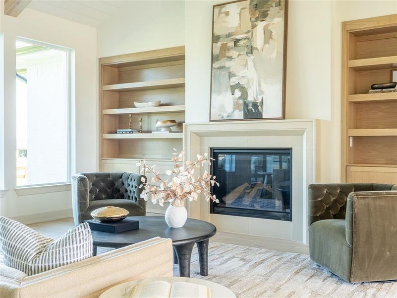 Sitting room with built in shelves, wood finished floors, a glass covered fireplace, and vaulted ceiling